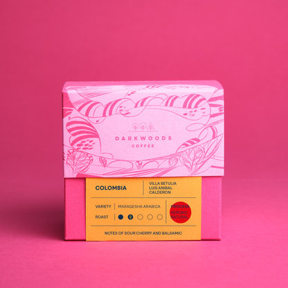 A packaged coffee product with iillustrated design on the upper half and a yellow label with text on the lower half, indicating the variety as 'Colombia Villa Betulia Ombligon' and the roast as 'Light'.